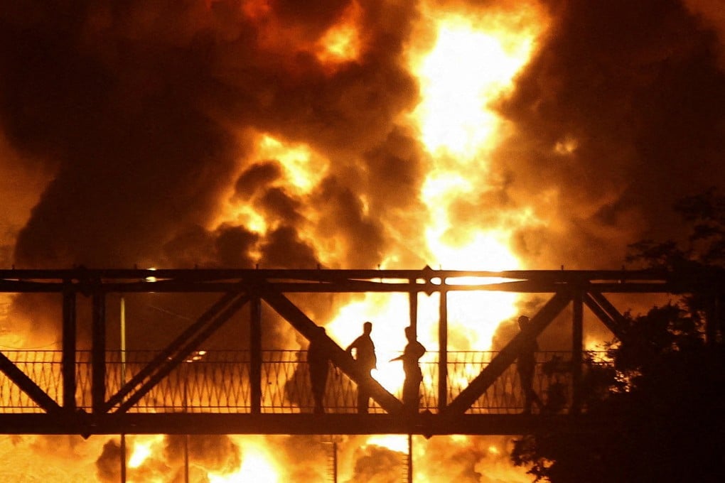 People watch from a bridge as flames from an Israeli attack rise from the Sharan Oil depot in Tehran, Iran, on June 15. Photo: Reuters