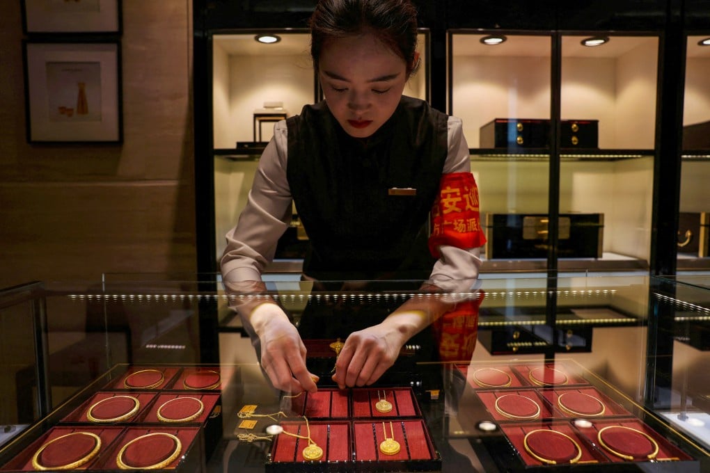 A staff member arranges gold necklaces in a display case at a Laopu Gold jewellery store in Beijing in March. Photo: Reuters
