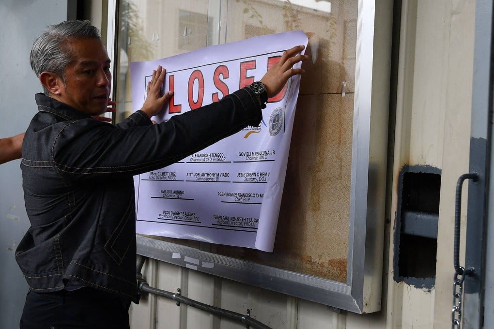 Philippine Interior Secretary Juanito Remulla places a closure sign at a Pogos hub last December. Photo: AFP