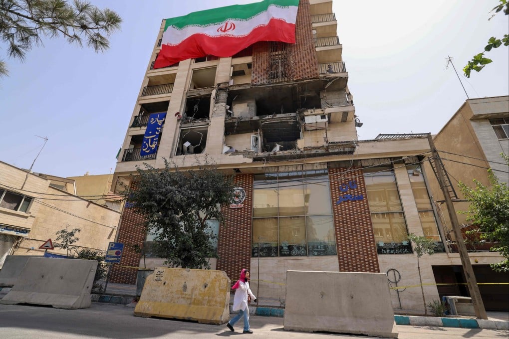 A woman walks past a damaged building in Tehran, Iran on Wednesday following Israeli strikes on the city. Photo: AFP