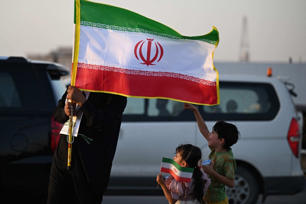 A man and children hold Iranian flags during celebrations in Basra, Iraq on Tuesday to mark the ceasefire between Israel and Iran. Photo: AFP