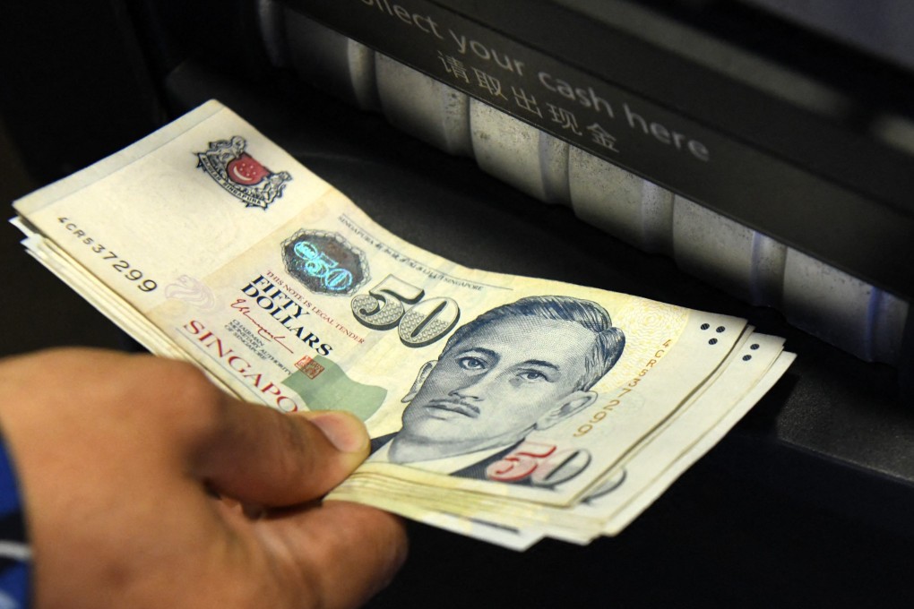 A man withdraws Singapore dollar banknotes from an ATM. Scam victims will still be allowed to withdraw funds for daily living expenses. Photo: AFP
