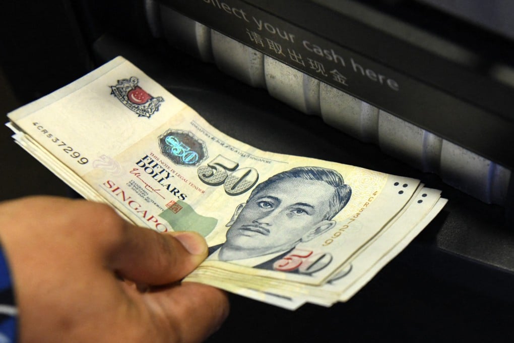 A man withdraws Singapore dollar banknotes from an ATM. Scam victims will still be allowed to withdraw funds for daily living expenses. Photo: AFP