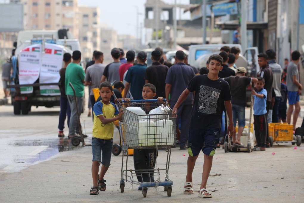 Palestinian children transport cans of water home as people queue at a water distribution point in Nuseirat, in the central Gaza Strip, on June 23. Photo: AFP