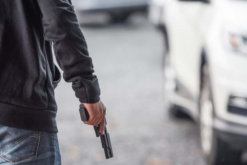 A man holds a gun in a car park. A series of gun attacks in the past few weeks have made Malaysians jittery. Photo: Shutterstock