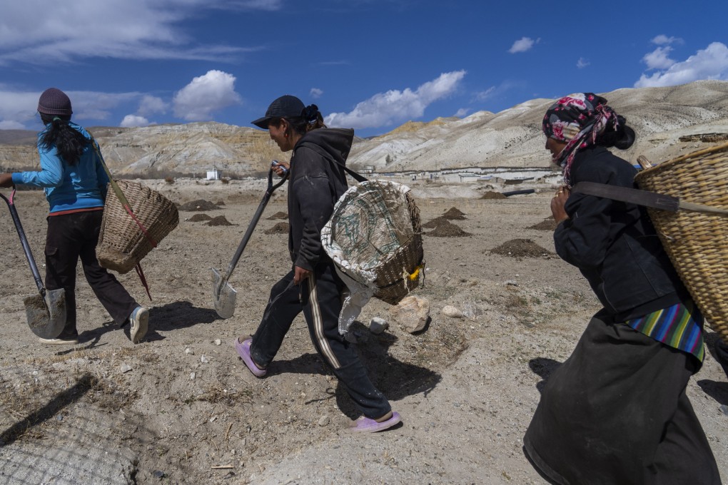Villagers walk towards a field to plant apple trees in the newly relocated settlement of the abandoned Samjung village on April 18.  Photo: AP
