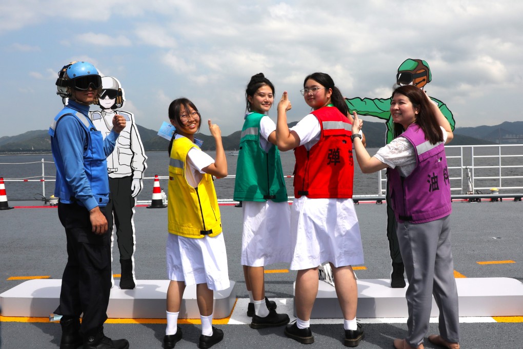 Visitors try on the coloured vests used by crew members on the deck of the Shandong. Photo: Xinhua