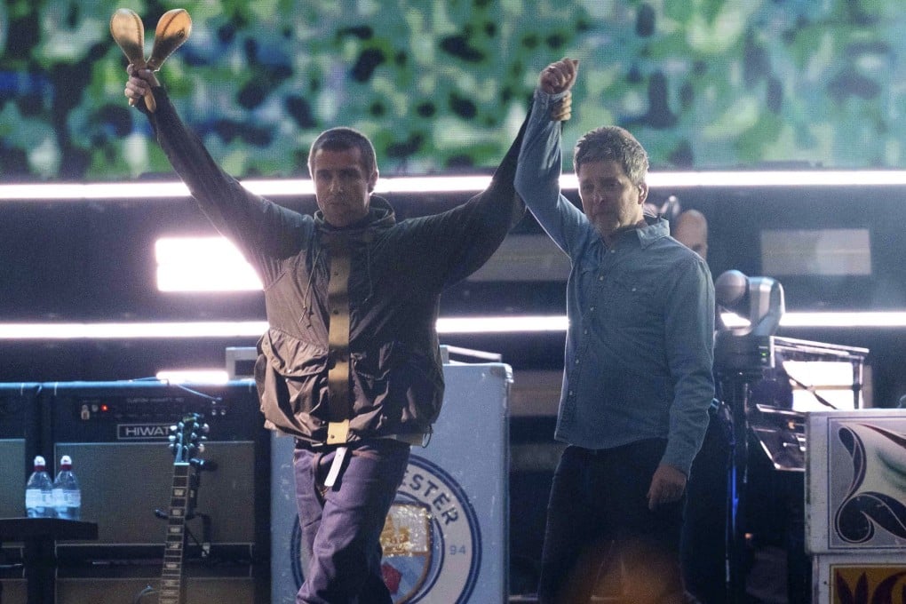 Liam Gallagher (left) holds hands with brother Noel during their reunion concert on Friday in Cardiff. Photo: AP