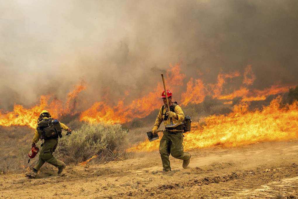Firefighters scrambles to keep the Madre Fire from crossing a dozer line as it makes a run along Highway 166, on Thursday in San Luis Obispo County, California. Photo: AP