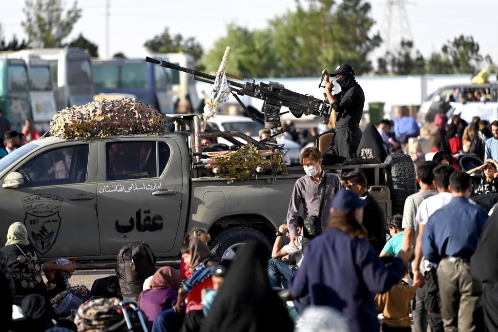 Taliban security personnel stand guard on the back of a vehicle as Afghan refugees arrive at the zero point of the Islam Qala border crossing between Afghanistan and Iran on June 28, following their deportation from Iran. Photo: AFP