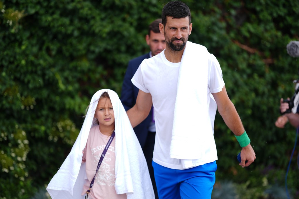 Novak Djokovic arrives with his daughter Tara for a practice session at the All England Club in Wimbledon. Photo: DPA