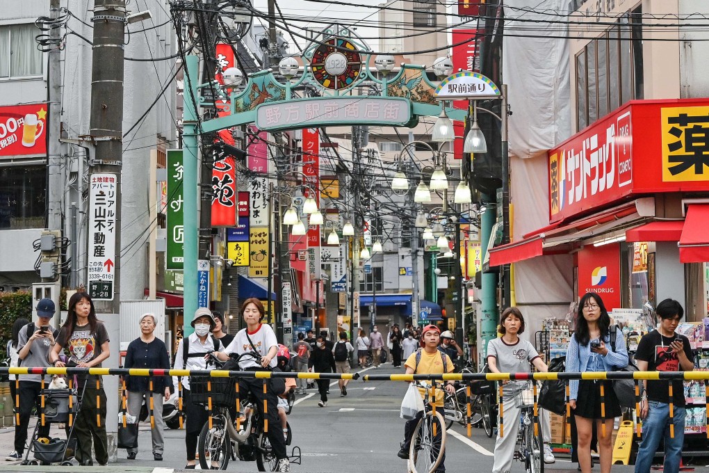 People wait at a level crossing along a shopping street in the Nakano ward of Tokyo. Real wages declined 2.9 per cent from a year earlier in May, Japan’s labour ministry reported on Monday. Photo: AFP