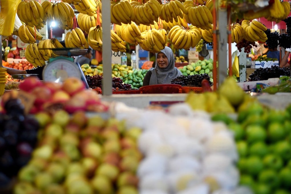 A Malaysian woman shops for fruit at a market in Kuala Lumpur. New taxes on apples and oranges were rolled back soon after their introduction. Photo: AFP