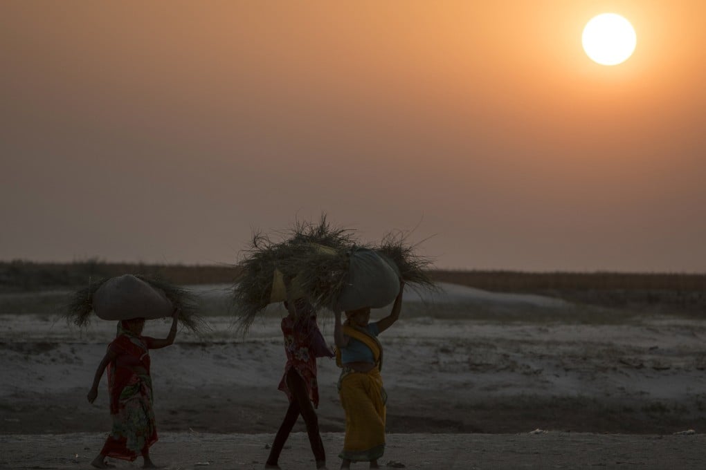 Indian farmers walk at sunset along the dry banks of a tributary of the river Ganges, in the Indian state of Bihar. Photo: AFP