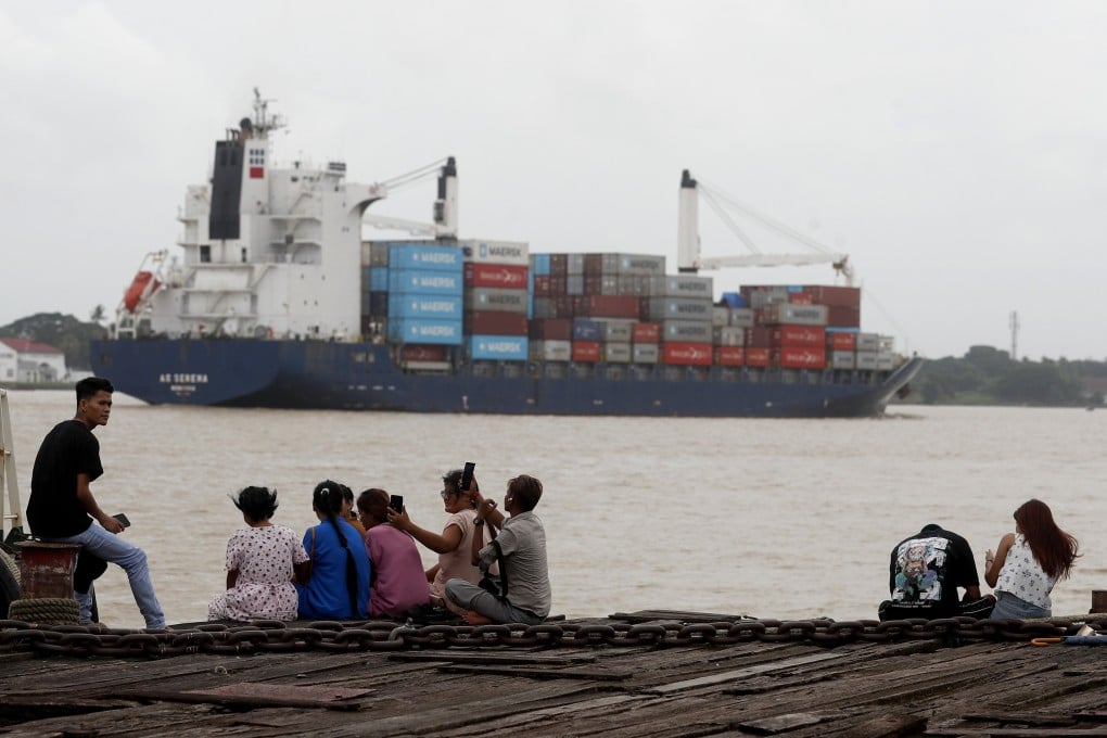 People relax at the jetty near the container cargo port on Wednesday as a container cargo ship passes by in Myanmar, which US President Donald Trump has threatened with a 40 per cent tariff. Photo: EPA