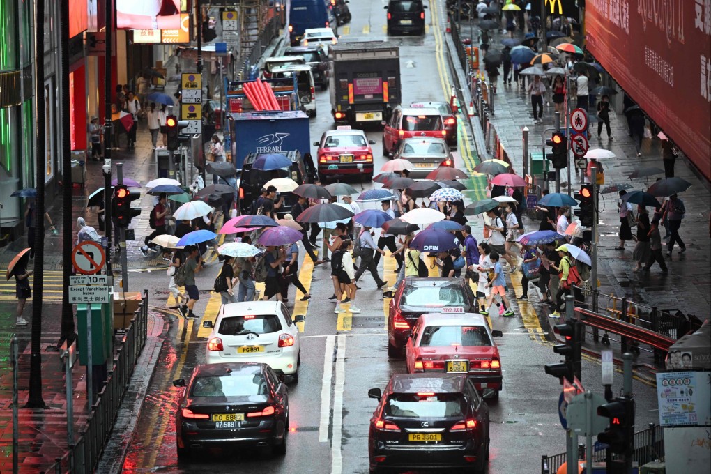 Pedestrians and cars make their way in heavy rain in Hong Kong on July 10, after the Observatory issued a red rainstorm warning signal. Photo: AFP