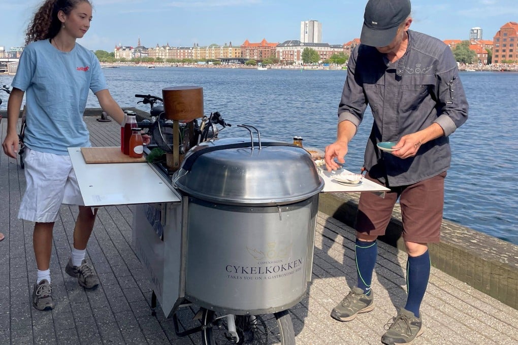 Danish chef Morten Kryger Wulff cooks on his self-designed kitchen-bike during a stop of a gastronomical bike tour on July 2 in Copenhagen, Denmark. Photo: AFP
