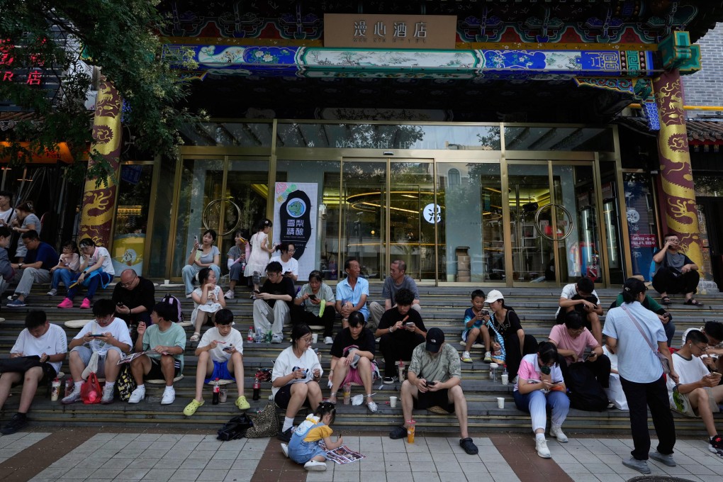 People scroll through their phones while sitting in front of a hotel in Beijing on July 13. Photo: AP