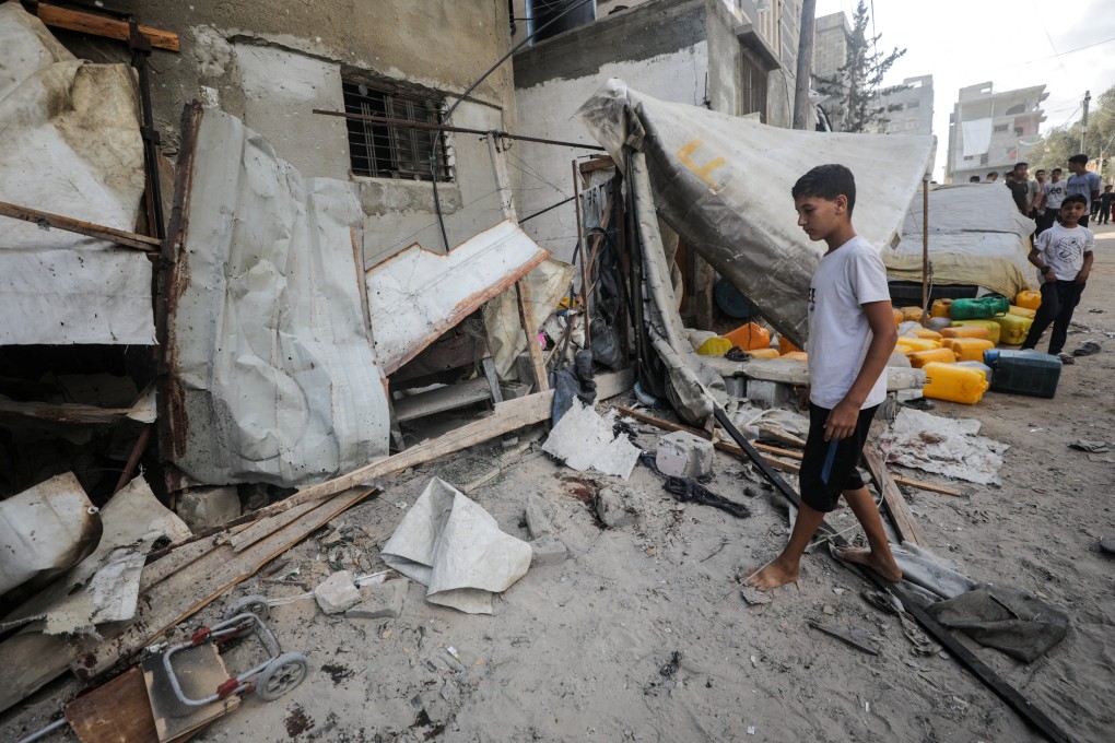 A Palestinian boy inspects the site of an Israeli strike that killed Palestinians as they gathered to collect water from a distribution point in Nuseirat, central Gaza on Sunday. Photo: Reuters