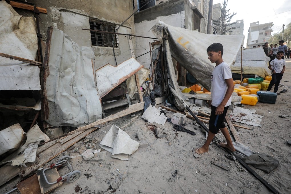 A Palestinian boy inspects the site of an Israeli strike that killed Palestinians as they gathered to collect water from a distribution point in Nuseirat, central Gaza on Sunday. Photo: Reuters