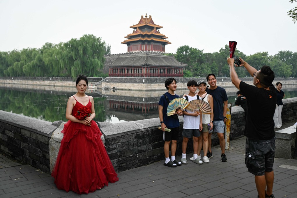 A woman wearing a wedding dress stands next a family taking a group photo near the Forbidden City in Beijing. Photo: AFP