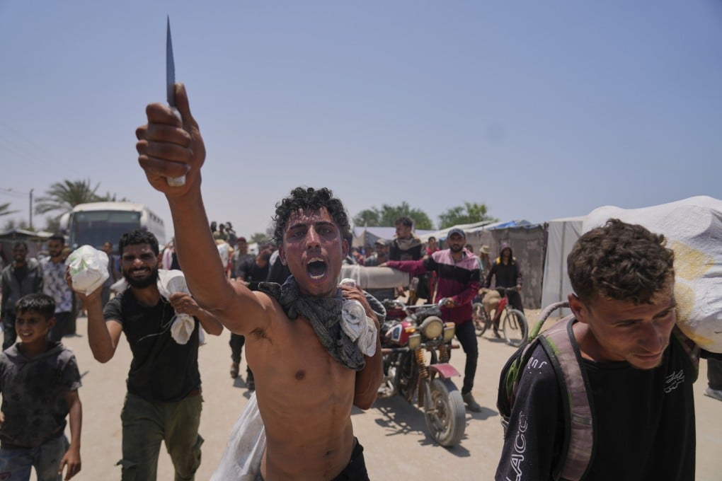 A Palestinian shouts to the camera in Arabic, “We get food with the taste of death and blood,” as he carries a bag containing food and humanitarian aid packages delivered by the Gaza Humanitarian Foundation in Rafah. Photo: AP