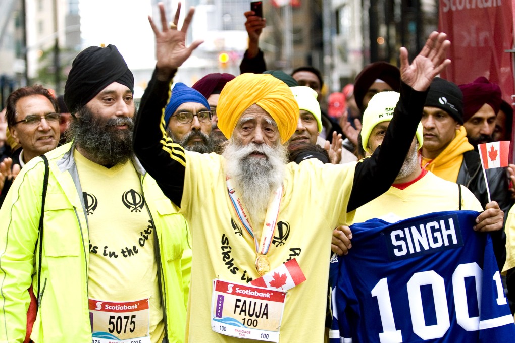 Fauja Singh (centre), then 100,  celebrates after completing the Toronto Waterfront Marathon in 2011. Photo: AP