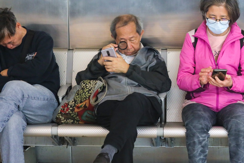 An elderly man looks at his mobile phone screen with the aid of a magnifying glass in Tsim Sha Tsui. Photo: Xiaomei Chen