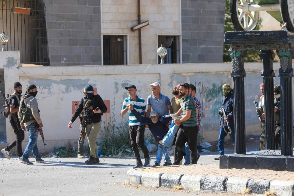 People carry a man wounded during clashes between Bedouin tribes and Druze fighers in an area between Mazraa and Walga near the predominantly Druze city of Sweida, Syria on Monday. Photo: AFP