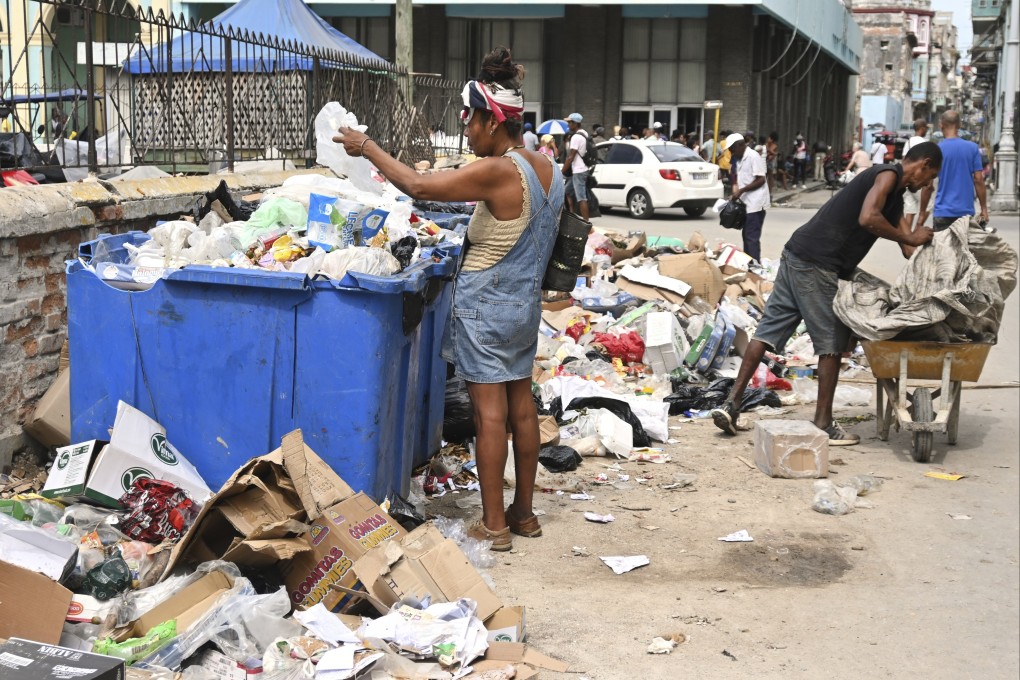A woman  in Havana, Cuba. searches through a dumpster looking for useful items. Photo: AP