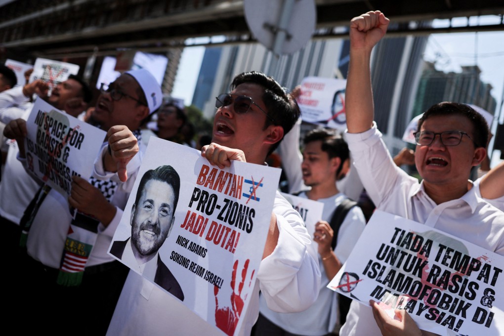 Protesters hold signs and a picture of US envoy nominee Nick Adams outside the US embassy in Kuala Lumpur on Friday. Photo: Reuters