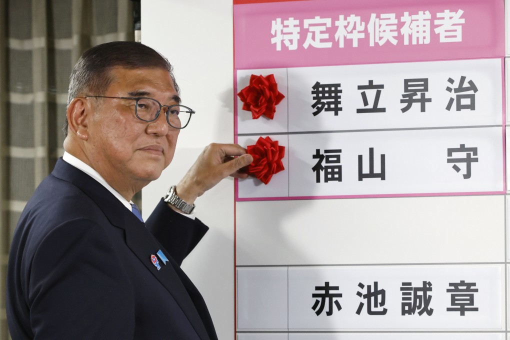 Japan’s Prime Minister Shigeru Ishiba, who heads the ruling Liberal Democratic Party, places a red paper rose on the name of an elected candidate, at the LDP headquarters in Tokyo on Sunday. Photo: AP