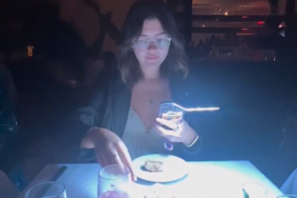 A food influencer is seen using an LED light to take photos and video in a restaurant, moments before the purported owner approaches her, in a still from an Instagram reel. Photo: Instagram/tooomuchfoood