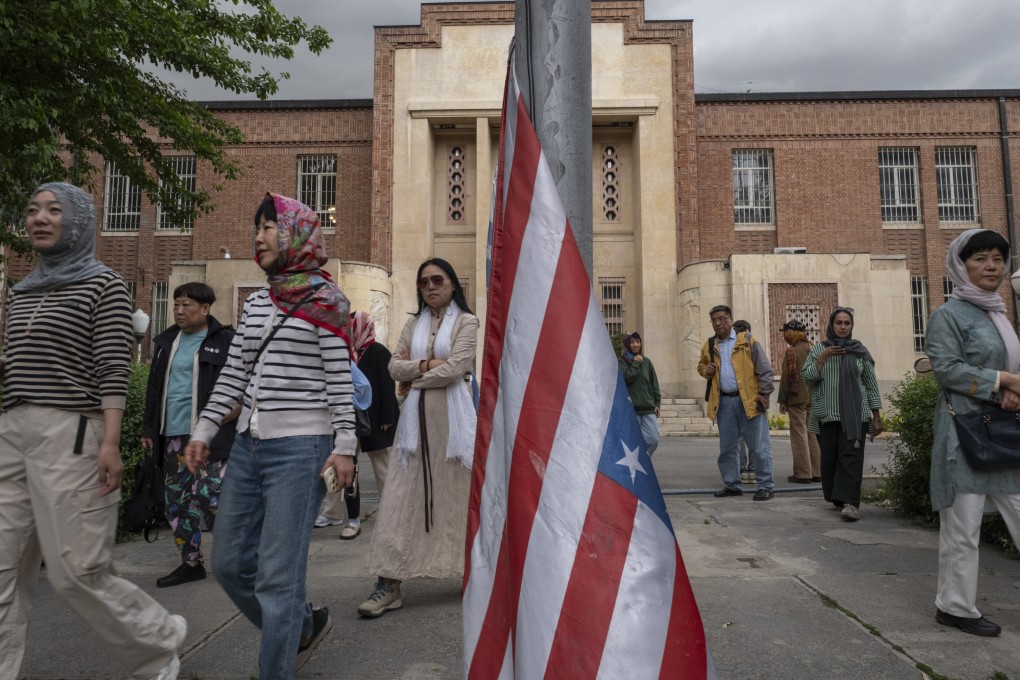 Tourists walk past the US flag after visiting the former US embassy in Tehran, Iran, in April 2025. A ceasefire between Iran and Israel is holding steady, but travellers remain on edge over the potential for instability. Photo: NurPhoto via Getty Images