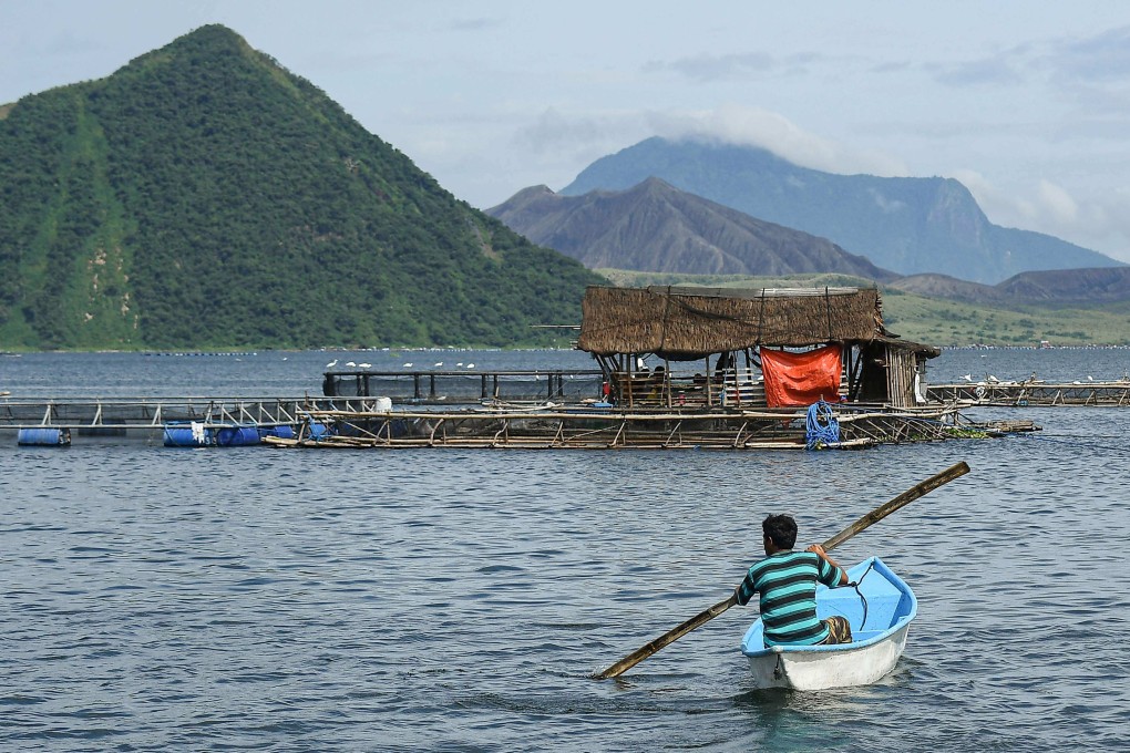 A fisherman rows his boat near fish cages on Taal Lake off Laurel municipality, at the foot of the Taal Volcano, on July 10. Photo: AFP