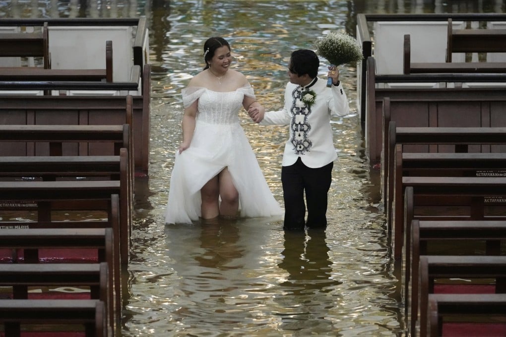 Newlyweds Jade Rick Verdillo (right) and Jamaica walk hand in hand during their wedding in a flooded church in the Philippines. Photo: AP