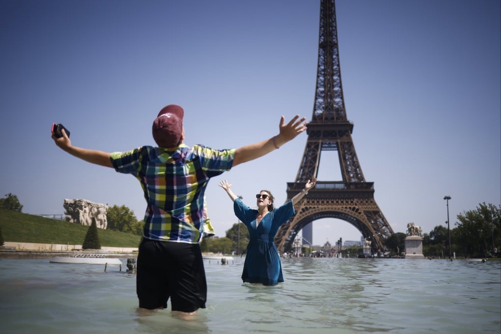 The Eiffel Tower is the backdrop for people cooling off during a Parisian heatwave. Photo: EPA