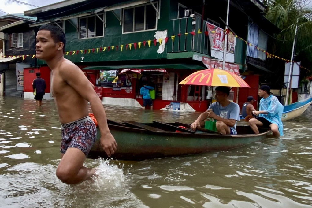People make their way through floodwaters on a wooden boat the town of Kawit, Cavite province, Philippines, on Thursday. Photo: EPA