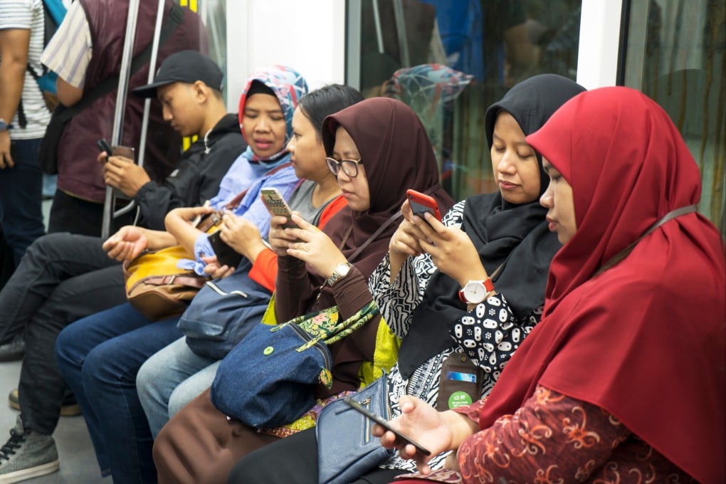Group of passengers using smartphones while sitting inside Jakarta MRT. Photo: Shutterstock