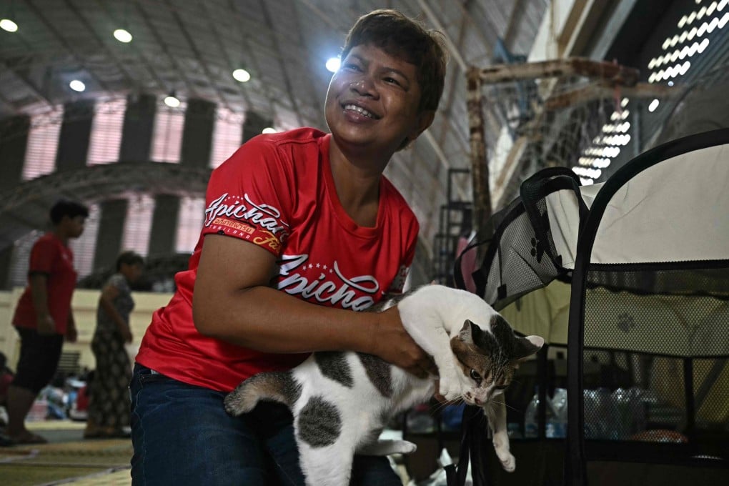 Pornpan Sooksai holds one of her cats as they take shelter in a gymnasium amid fighting between Thailand and Cambodia. Photo: AFP