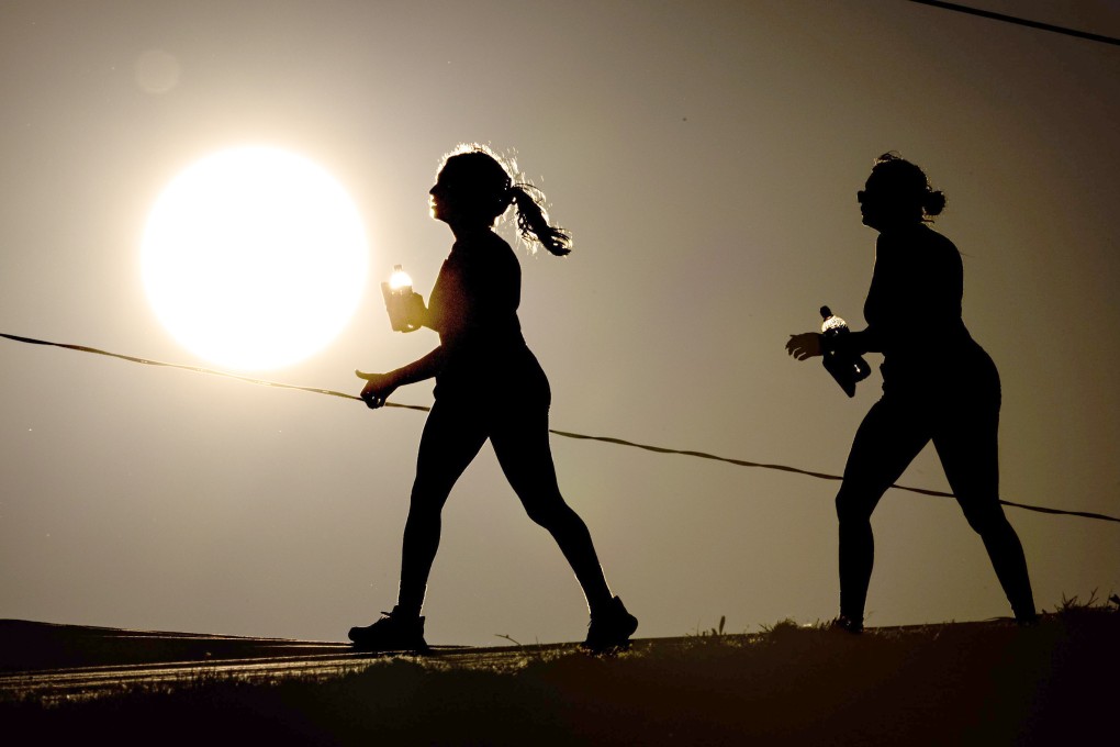 Pedestrians carry water while walking in Dallas on Friday. Photo: Photo: TNS