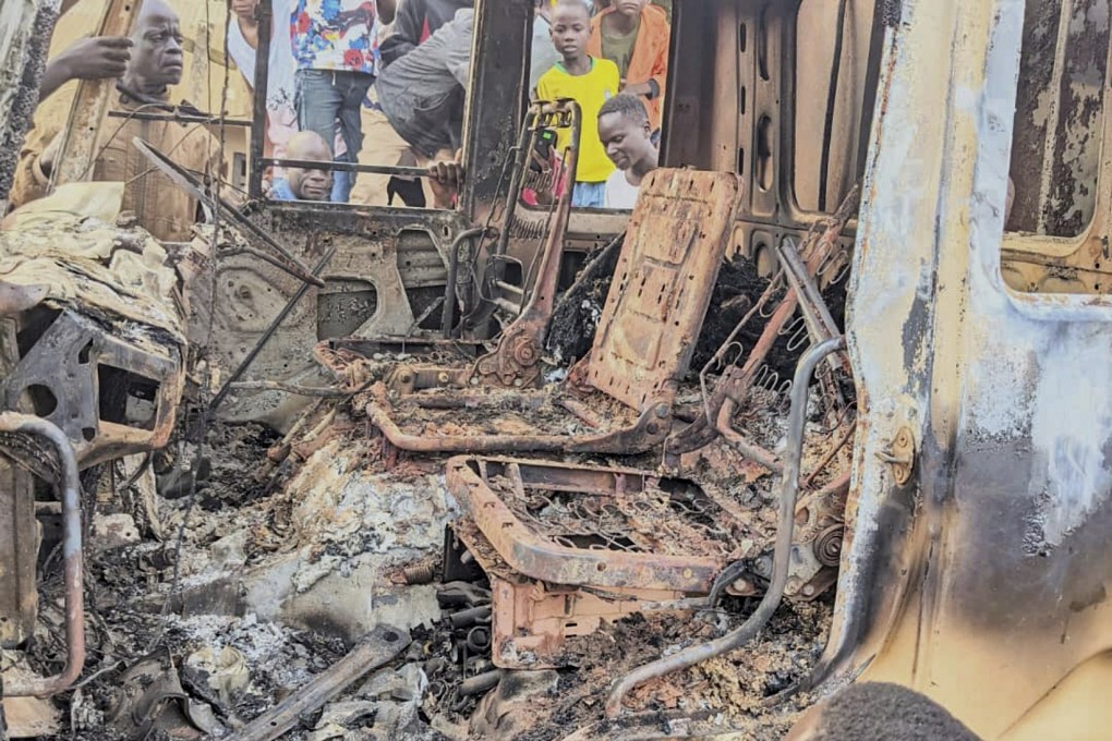 People gather around the charred remains of a burned vehicle following a deadly attack in Komanda, Ituri province of eastern DR Congo on Sunday. Photo: UGC via AP
