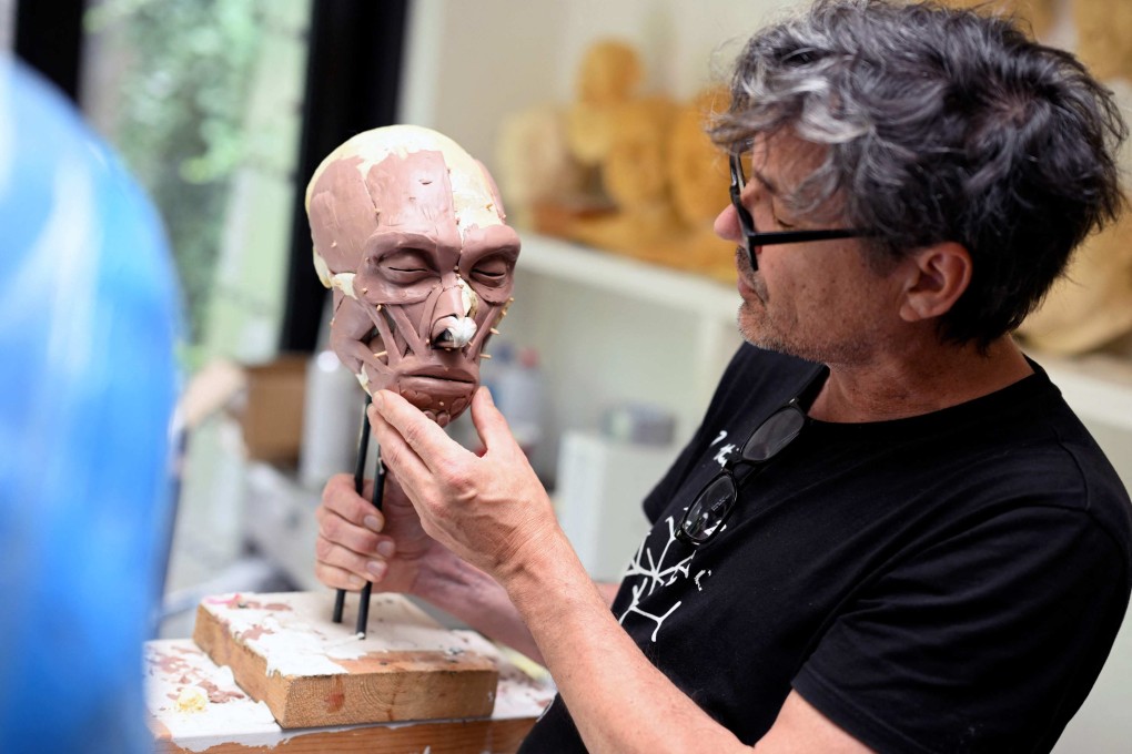 Dutch artist Alfons Kennis holds a model under construction representing a prehistoric human skull in his workshop in Arnhem, on July 3, 2025. Alfons and his twin brother Adrie are known for their paleo-anthropological work. Photo: AFP