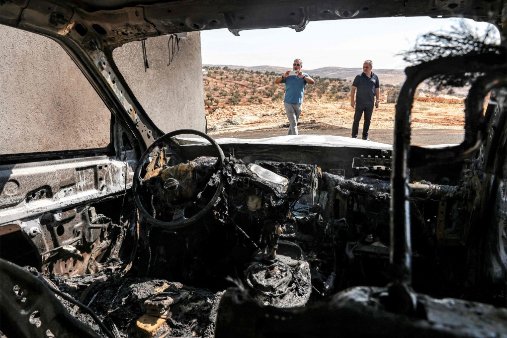 Men stand near a vehicle that was reportedly torched by Israeli settlers during an overnight attack on the Palestinian Christian village of Taybeh, northeast of Ramallah in the occupied West Bank, on Monday. Photo: AFP