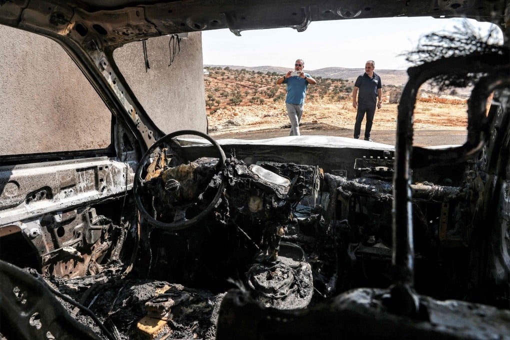 Men stand near a vehicle that was reportedly torched by Israeli settlers during an overnight attack on the Palestinian Christian village of Taybeh, northeast of Ramallah in the occupied West Bank, on Monday. Photo: AFP