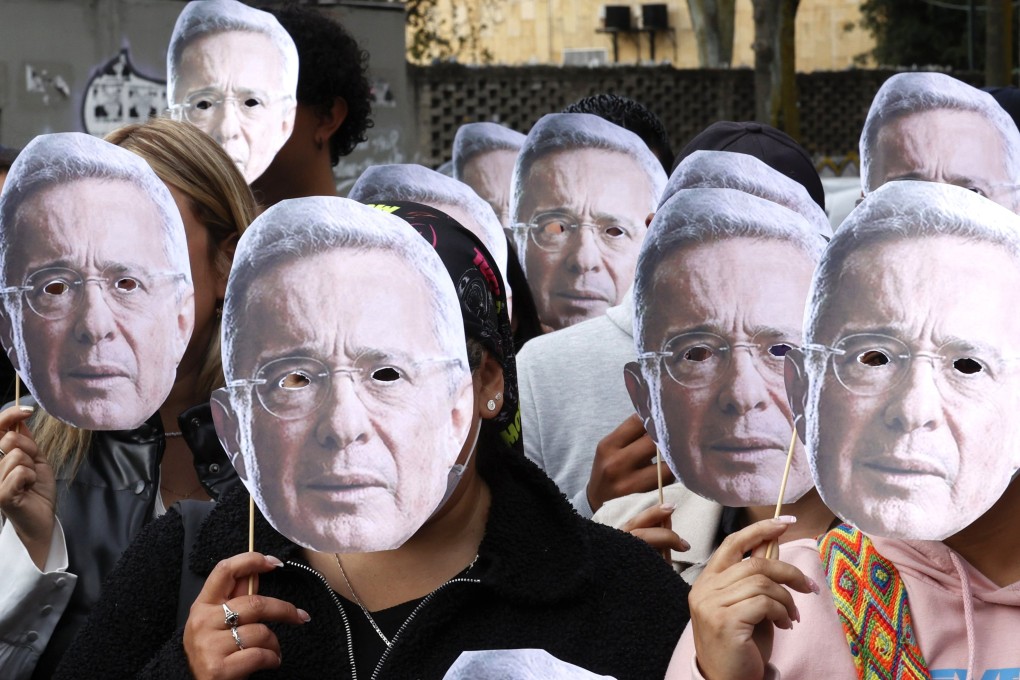 Alvaro Uribe’s supporters wear masks of the former Colombian president as they gather outside the Paloquemao Judicial Complex in Bogota, Colombia, on Monday. Photo: EPA