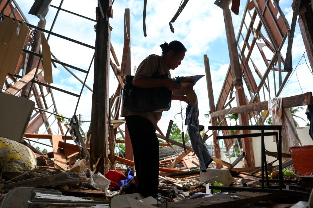 A 68-year-old Thai woman collects belongings from her home, destroyed by Cambodian artillery attacks, on Tuesday. Photo: Reuters