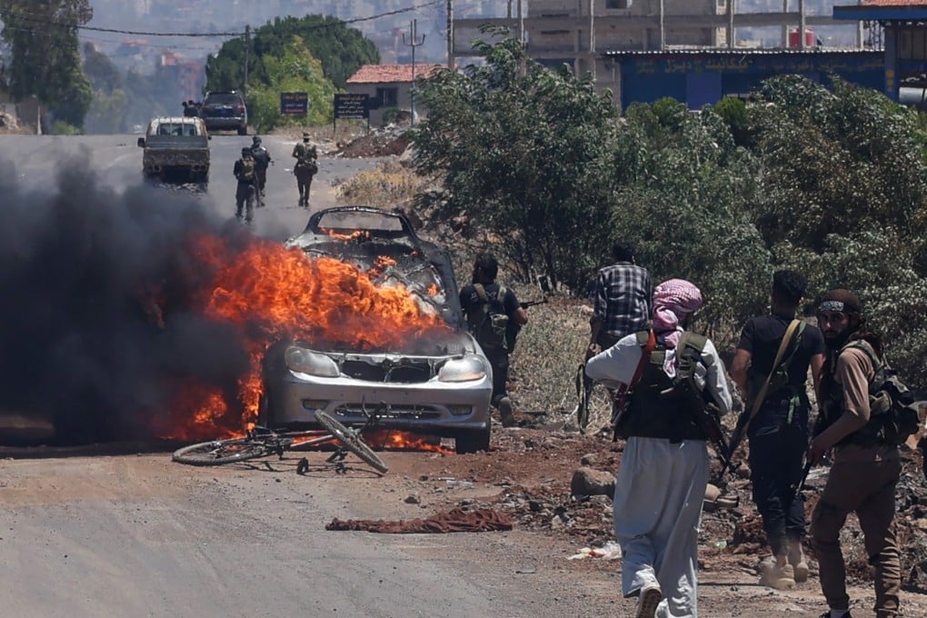 Bedouin and tribal fighters deploy as a car burns at the western entrance of Syria’s Druze heartland of Sweida on July 18. Photo: AFP/Getty Images/TNS