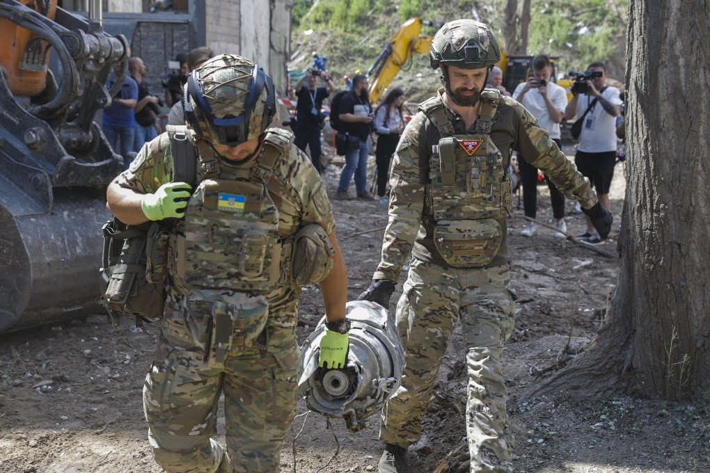 Experts carry a part of the rocket on Friday at the site of a rocket strike on a building in Kyiv. Photo: EPA