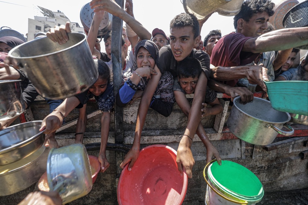 Internally displaced Palestinians, including children, hold pots as they gather to receive food from a charity kitchen, in Gaza City on Monday. Photo: EPA